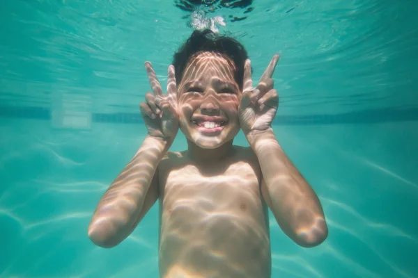 Niño lindo posando bajo el agua en la piscina — Foto de Stock