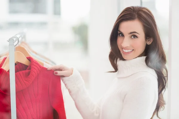Smiling brunette looking at clothes on rail — Stock Photo, Image