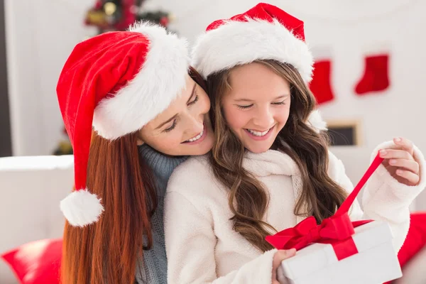 Festive mother and daughter on the couch with gift — Stock Photo, Image