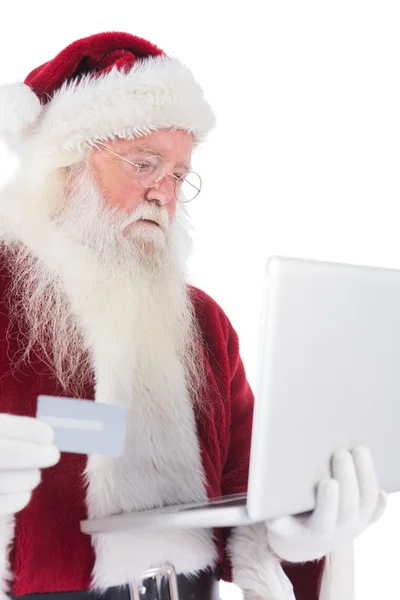 Papai Noel paga com cartão de crédito em um laptop — Fotografia de Stock