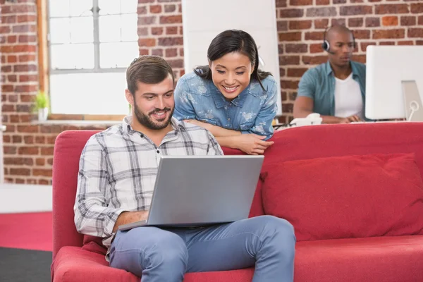 Colleagues using laptop on couch — Stock Photo, Image