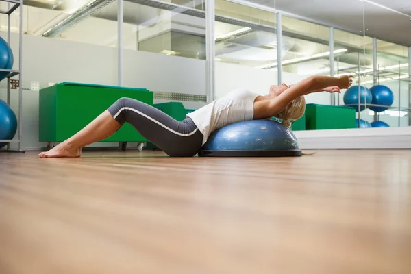 Seitenansicht einer Frau, die sich im Fitnessstudio den Rücken reckt — Stockfoto