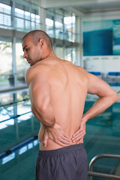 Rear view of shirtless swimmer with back ache by pool — Stock Photo, Image