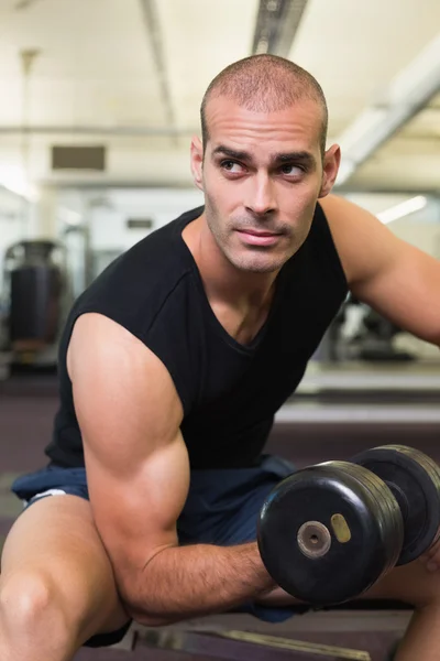 Joven haciendo ejercicio con la mancuerna en el gimnasio — Foto de Stock