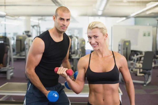 Pareja haciendo ejercicio con pesas en el gimnasio — Foto de Stock