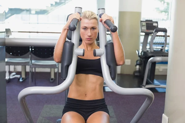 Ajuste mujer joven utilizando la máquina de fitness en el gimnasio —  Fotos de Stock