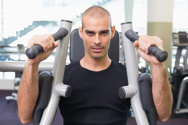 Serious man working on fitness machine at gym — Stock Photo, Image