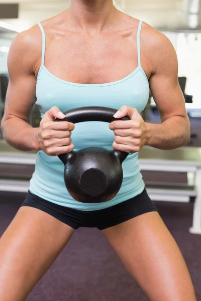 Sezione centrale di una donna che solleva il campanello del bollitore in palestra — Foto Stock