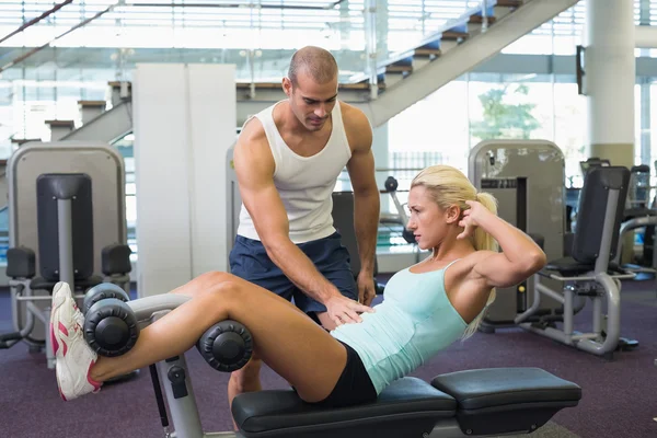 Männertrainer hilft Frau bei Bauchkrämpfen im Fitnessstudio — Stockfoto