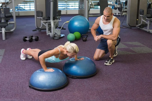 Male trainer assisting woman with push ups at gym — Stock Photo, Image