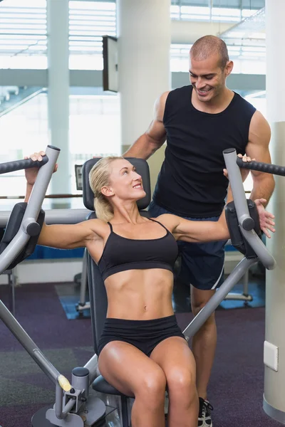 Trainerin hilft Frau an Fitnessgerät im Fitnessstudio — Stockfoto