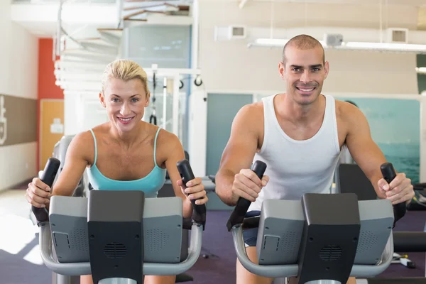 Pareja en forma trabajando en bicicletas estáticas en el gimnasio —  Fotos de Stock