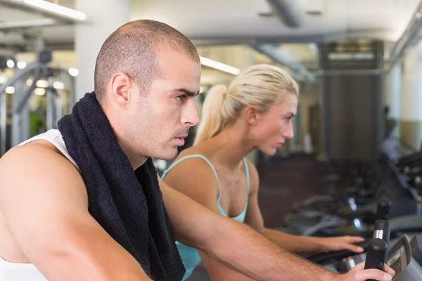 Beslutsamt passar par arbetar på motionscyklar på gym — Stockfoto
