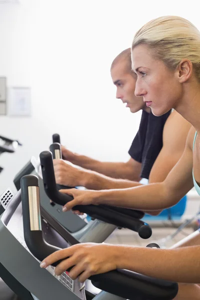 Beslutsamt passar par arbetar på motionscyklar på gym — Stockfoto