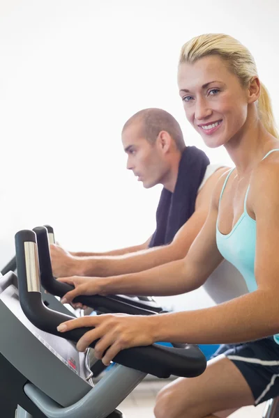 Fit casal trabalhando em bicicletas de exercício no ginásio — Fotografia de Stock