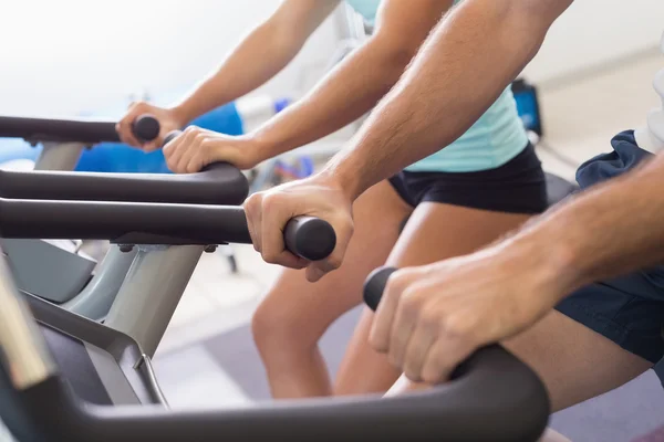 Seção intermediária do casal trabalhando em bicicletas de exercício no ginásio — Fotografia de Stock