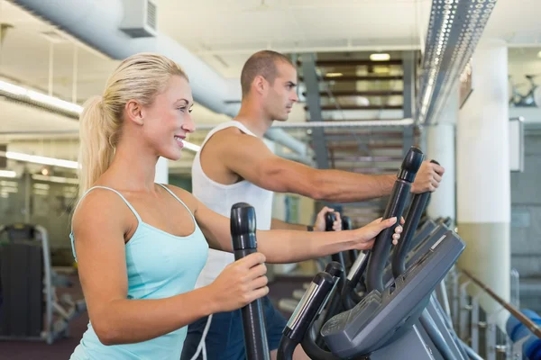 Adatto a giovani coppie che lavorano su x-trainer in palestra — Foto Stock