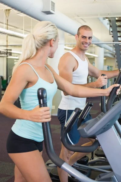 Fit young couple working on x-trainers at gym — Stock Photo, Image