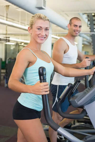 Fit jovem casal trabalhando em x-trainers no ginásio — Fotografia de Stock