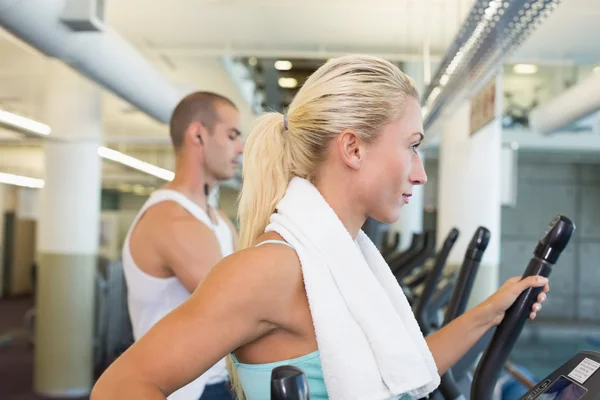 Seitenansicht eines Paares, das im Fitnessstudio an X-Trainern arbeitet — Stockfoto