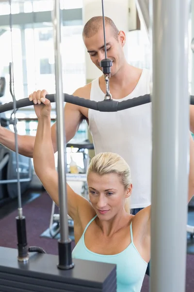 Treinador masculino assistindo mulher na máquina lat no ginásio — Fotografia de Stock