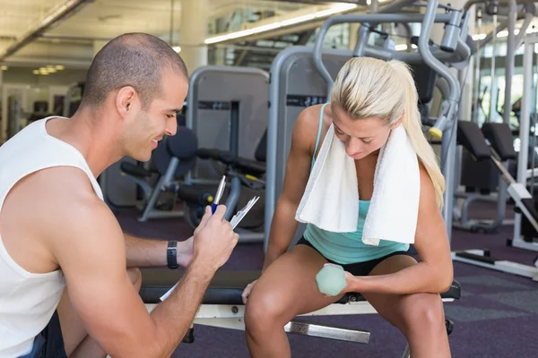 Mannelijke trainer vrouw met dumbbell bijstaan in gym — Stockfoto