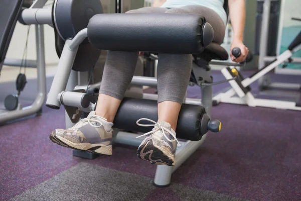 Adatto donna utilizzando pesi macchina per le gambe — Foto Stock