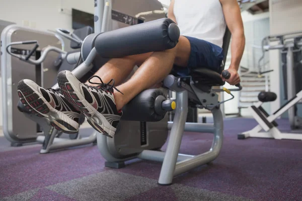 Ajuste el hombre usando la máquina de pesos para las piernas — Foto de Stock