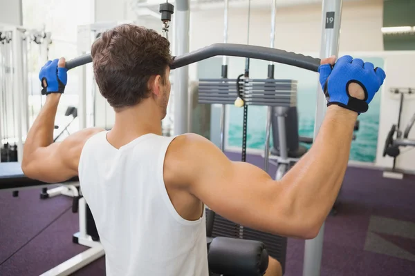 Fit man using weights machine for arms — Stock Photo, Image