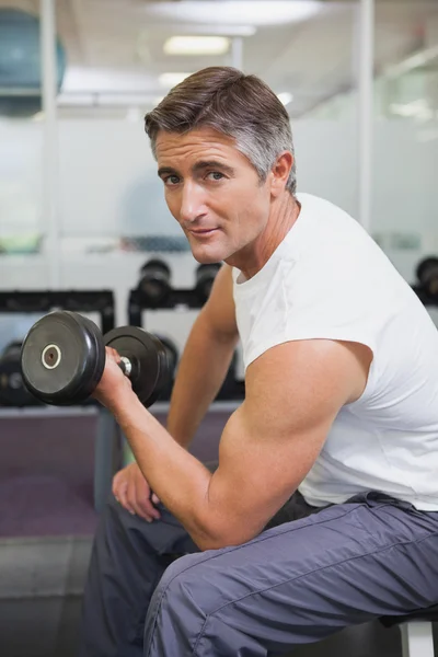 Hombre en forma levantando pesas sentado en el banco — Foto de Stock