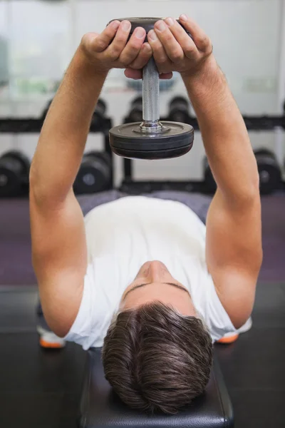 Fit man lifting dumbbell lying on the bench — Stock Photo, Image