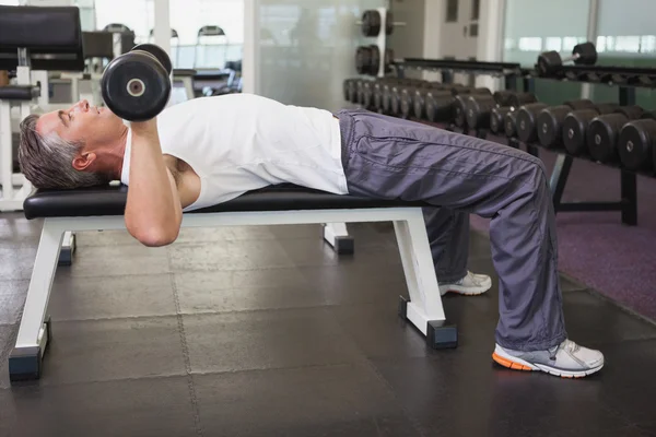 Fit man lifting dumbbells lying on the bench — Stock Photo, Image