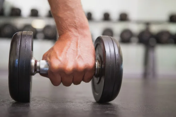 Fit man lifting heavy black dumbbell — Stock Photo, Image