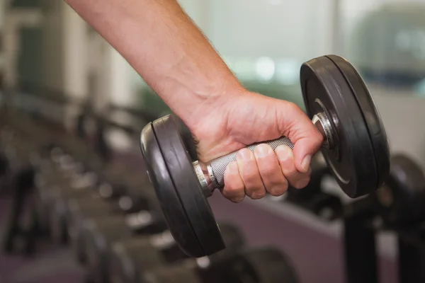 Fit man lifting heavy black dumbbell — Stock Photo, Image