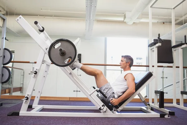 Fit man lifting heavy barbell with legs — Stock Photo, Image