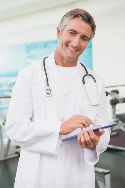 Confident doctor standing in fitness studio using tablet pc — Stock Photo, Image
