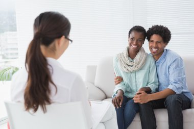 Reconciled couple smiling at their therapist clipart