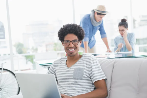 Ung kreativ man använder laptop på soffan — Stockfoto