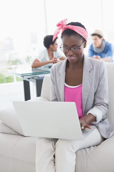 Young creative woman using laptop on couch — Stock Photo, Image