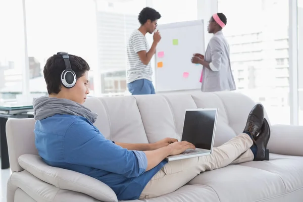 Pemuda kreatif menggunakan laptop di sofa — Stok Foto