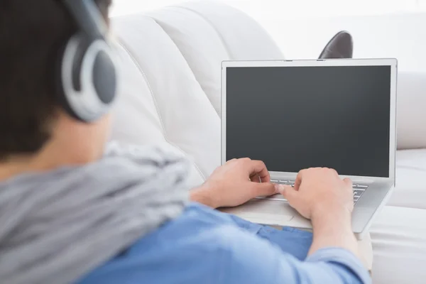 Young creative man using laptop on couch — Stock Photo, Image