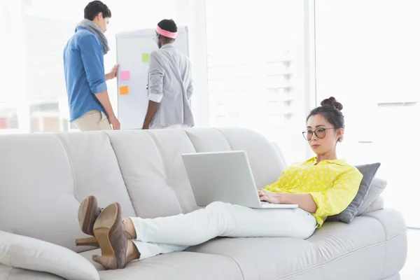 Young creative woman using laptop on couch — Stock Photo, Image