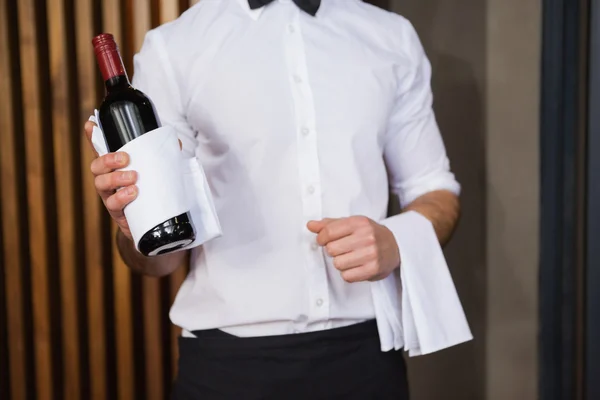 Stilig servitör håller en flaska rött vin och en handduk — Stockfoto