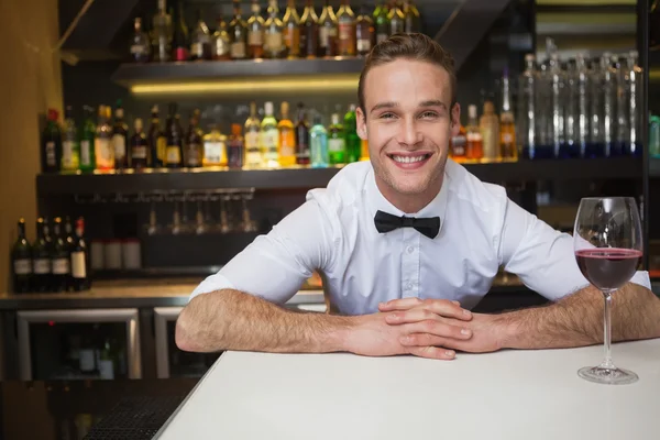 Smiling bartender having glass of red wine — Stock Photo, Image