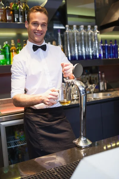 Handsome barkeeper pulling a pint of beer — Stock Photo, Image