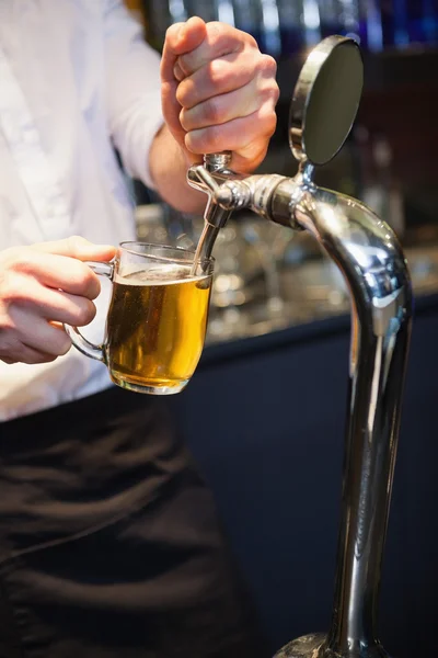 Handsome barkeeper pulling a pint of beer — Stock Photo, Image