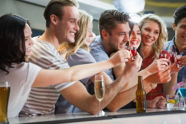 Happy friends holding cocktails into shot glasses — Stock Photo, Image