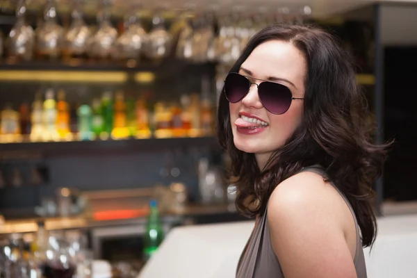 Pretty woman wearing sunglasses with tongue out — Stock Photo, Image