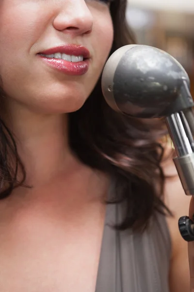 Usměvavá brunetka zpěv s její mikrofonu — Stock fotografie