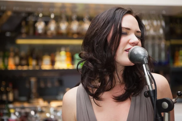 Brunette femme aux cheveux chantant dans un microphone — Photo